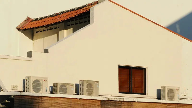 Older white building with several split AC units mounted on the roof edge